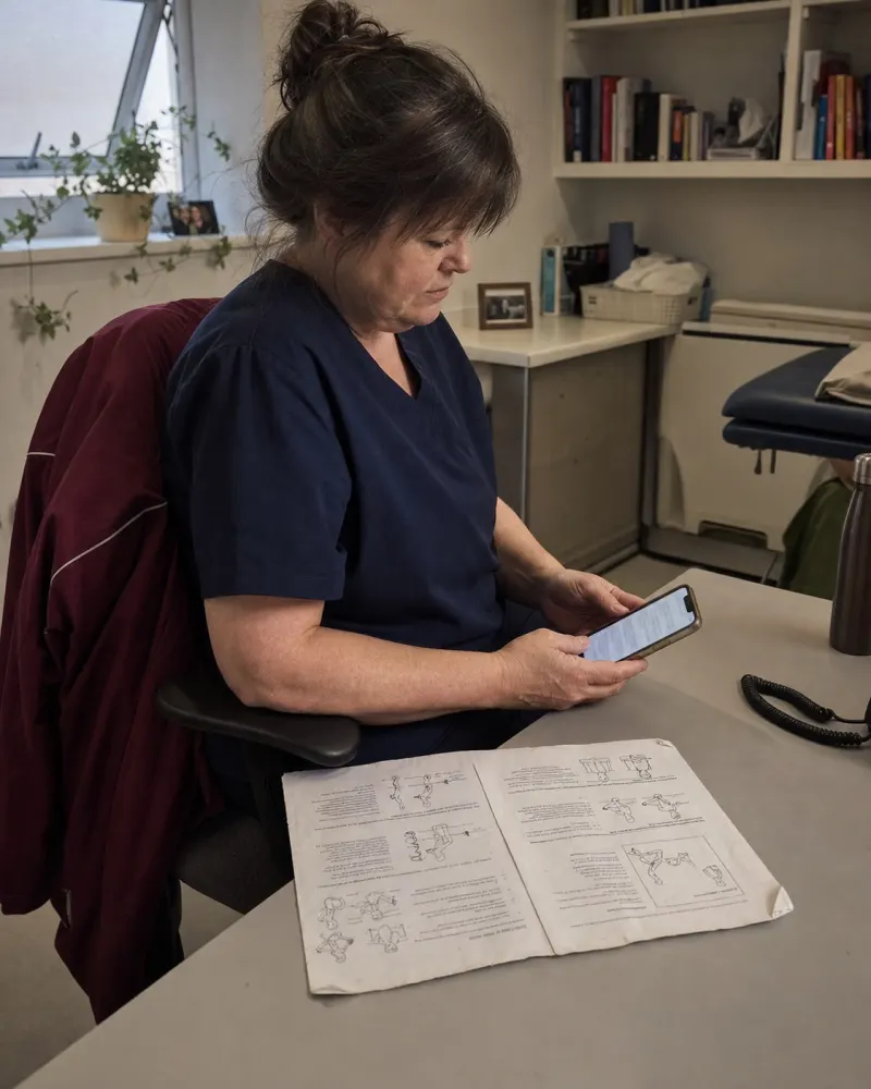 A physiotherapist's back office at the end of the day, a client's message open on the phone and the worn two-page exercise sheet they hand out.